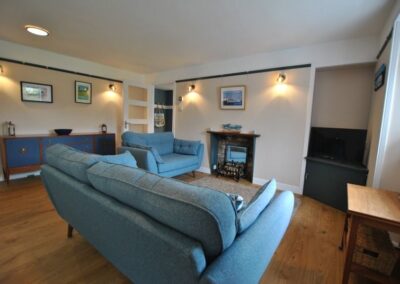 Lounge with two blue sofas pointed towards a fireplace and TV.