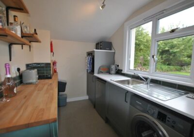 Galley kitchen with large window in front of the sink. There is a dishwasher and washing machine.