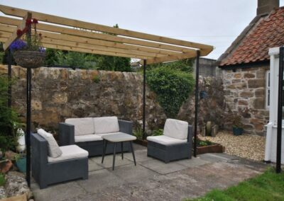 Outdoor furniture on a patio beneath a pergola.