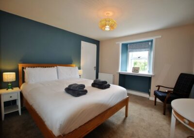 View across double bed towards a door and window.