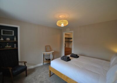 Double bed with white linen. There is a pile of towels on the bed.