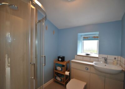 Shower unit opposite WC and sink beneath a small window.