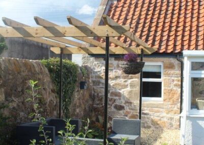 Seating area beneath a pergola, near the sunroom.