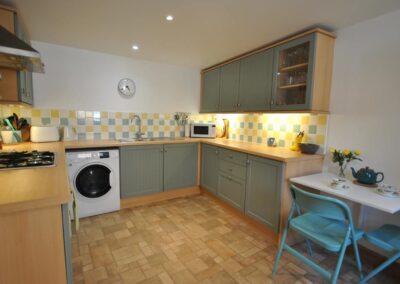 Kitchen units with green painted doors and yellow, green and white tiles.