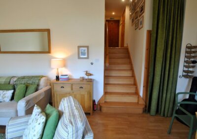 Wooden staircase leading up to a hallway, to the right of the lounge.