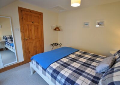 View from headboard towards a white framed, full length mirror next to the door at the foot of the bed.