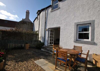 View of patio area looking towards the house and open French windows, up a few steps.