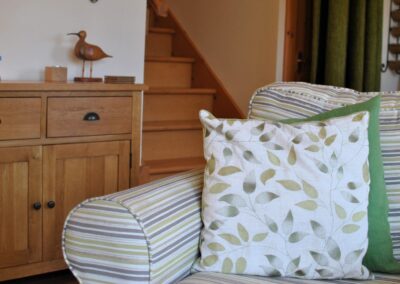 Detail of white and green cushion with leaf motif on a striped armchair.