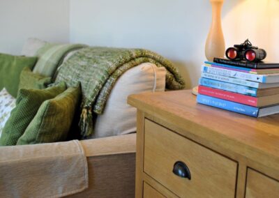 Pile of books and binoculars on a sideboard next to the sofa.