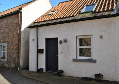 View of front of cottage with red tile roof and roof windows.