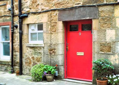 Bright red door with number 9 on a stone house.