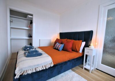 Navy blue and orange furnished bed to the left of a glass door.