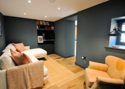 Corner sofa and armchair with TV and shelves of books.