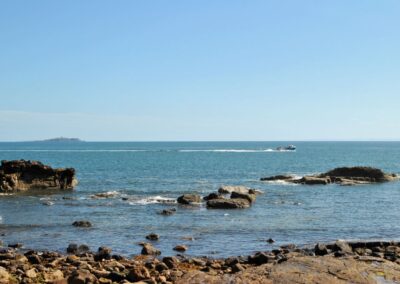 A fishing boat crosses the waves in front of the Isle of May.