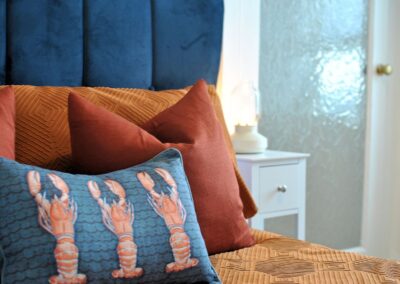 Cushion with three red lobsters on a bed.