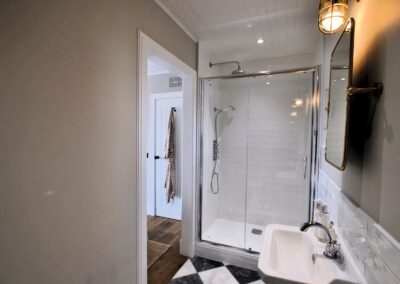 Walk-in shower in room decorated in white tiles and neutral colours.