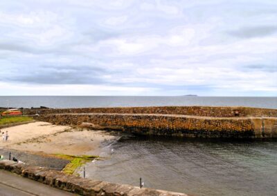 View of the Isle of May across the harbour. There is a small sandy beach at the end of the harbour.