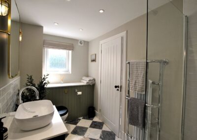 Black and white tiled floor, white bathroom suite and walk-in shower.