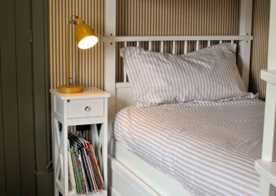 Striped bedclothes on white wooden bunks.