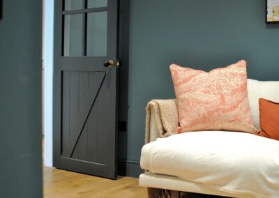 Dark painted doors and walls contrasted with white and peach textiles.