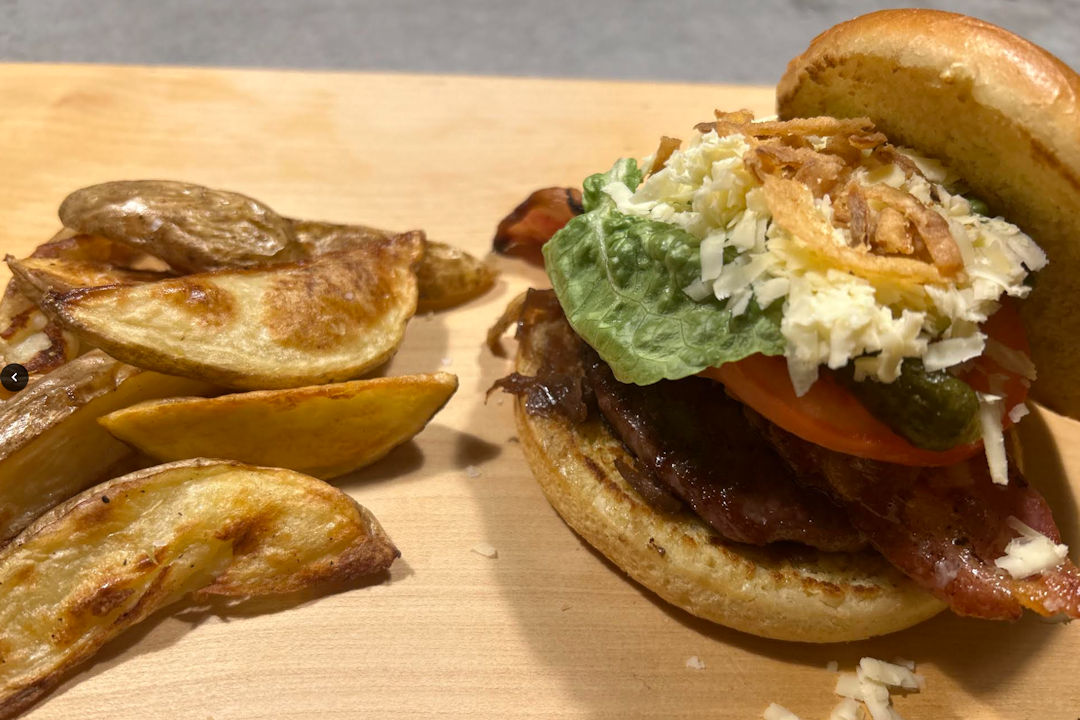 Burger with lettuce, tomato and cheese with thick fries.