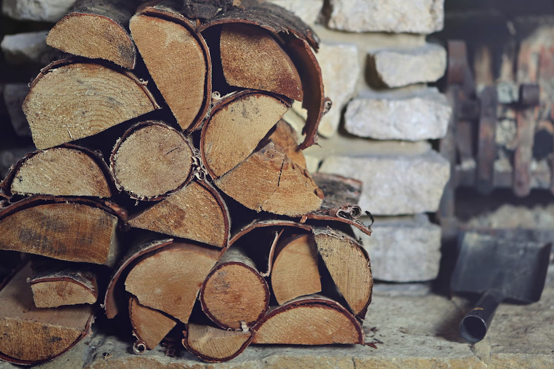 Pile of logs next to a fireplace.