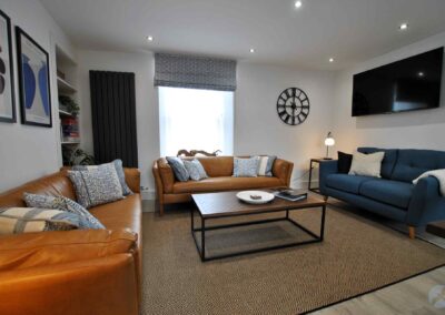 Lounge with three sofas against three walls, with a window behind the centre sofa.