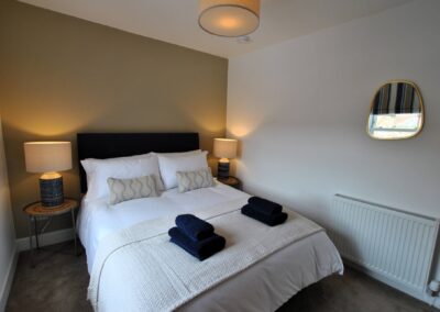 Double bed between bedside tables and lamps.