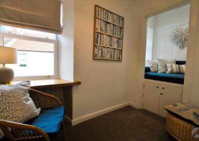 On the left a seat next to a desk built into the window; on the right a window seat with cushions.