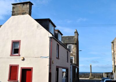 Gable end of three story house on a street leading to a sea wall.