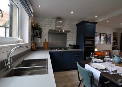 View down the length of a kitchen counter with a large sink in front of the window.