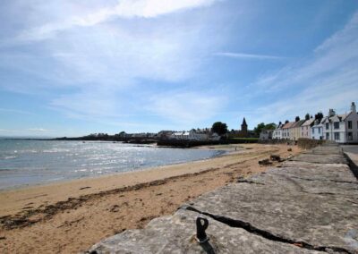 View over a wall towards a long beach that curves to the left towards Anstruther Wester.