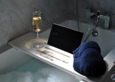 Bubble bath with a tray across the bath holding a glass of sparkling wine, an iPad and a towel.