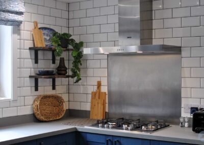 Gas hob with stainless steel backsplash against a white tiled kitchen wall.