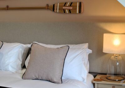 Detail of neutral cushions and white pillowcases next to a bedside lamp.